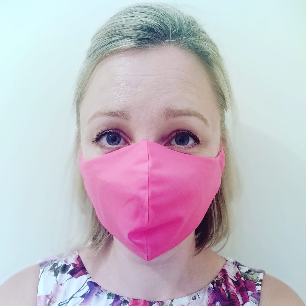Jennifer dressed for a wedding with a bright pink face mask on.